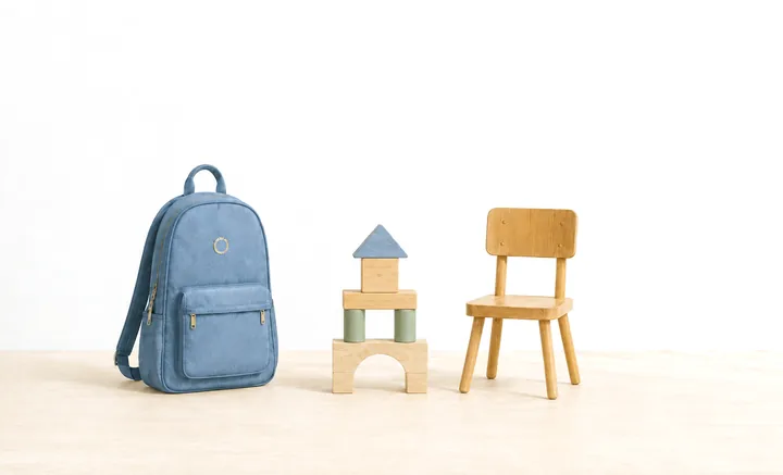 A blue backpack, a small block tower and a child’s wooden chair.